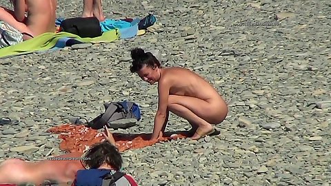 Voyeur nudist gets down to chill on the beach with other people also nude